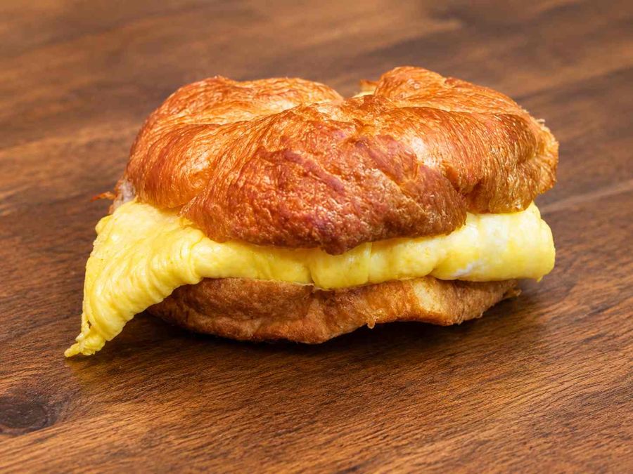 A croissant split and filled with folded scrambled egg and melted cheese.
